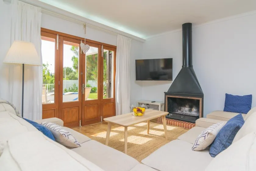 Una sala luminosa con asientos, una mesa de centro y puertas de vidrio hacia un patio.