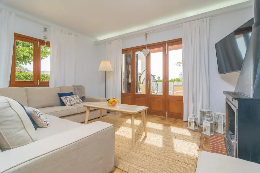 Una sala luminosa con asientos, una mesa de centro y puertas de vidrio que dan a un balcón.