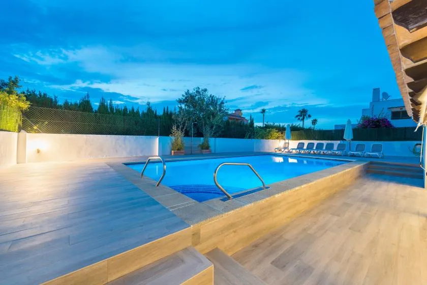 Una piscina al aire libre está rodeada por una terraza y asientos.