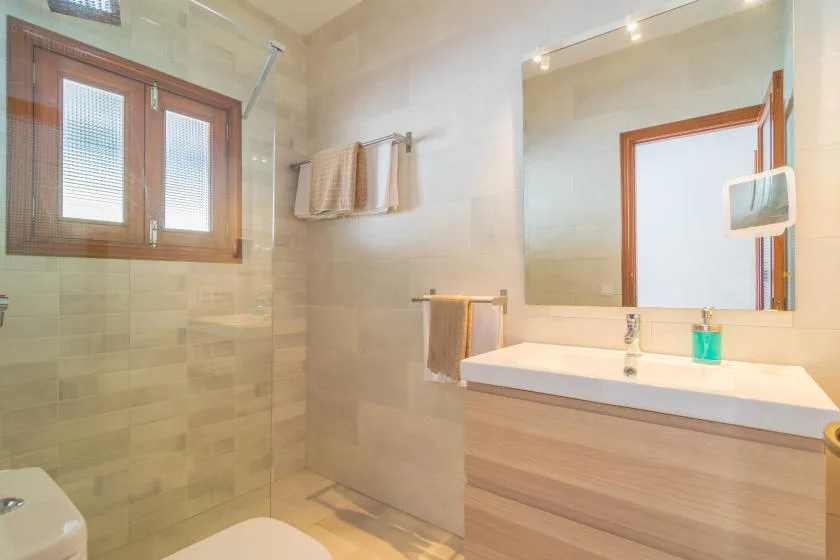 Un baño con azulejos, tocador, espejo y mampara de ducha de vidrio.