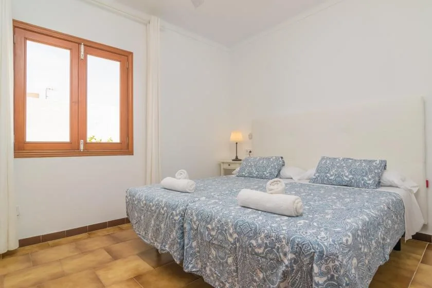 Un dormitorio con una cama grande cubierta con ropa de cama azul estampada junto a una ventana.