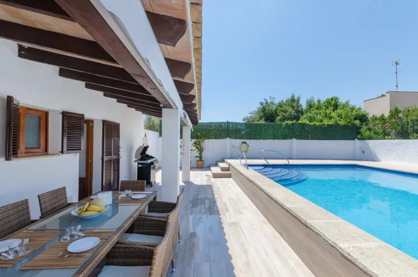 Una zona de comedor exterior cubierta junto a una piscina.