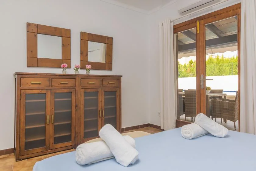 Un dormitorio con un mueble de madera y una cama con toallas dobladas.