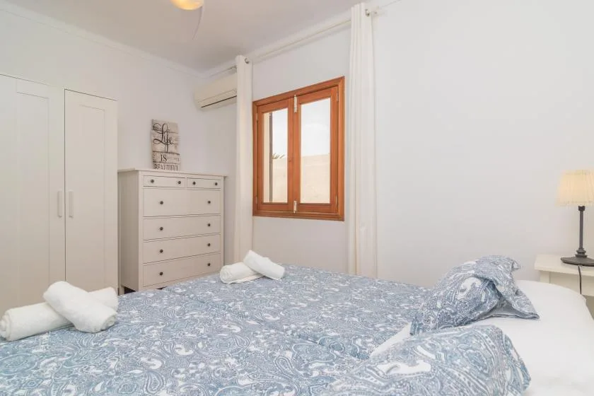 Un dormitorio con una colcha estampada y una ventana con marco de madera.