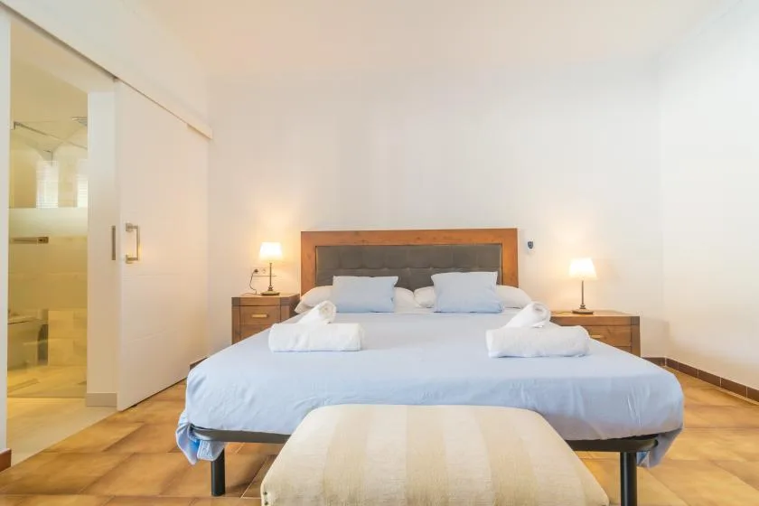 Un dormitorio con una cama bien tendida y lámparas a ambos lados.