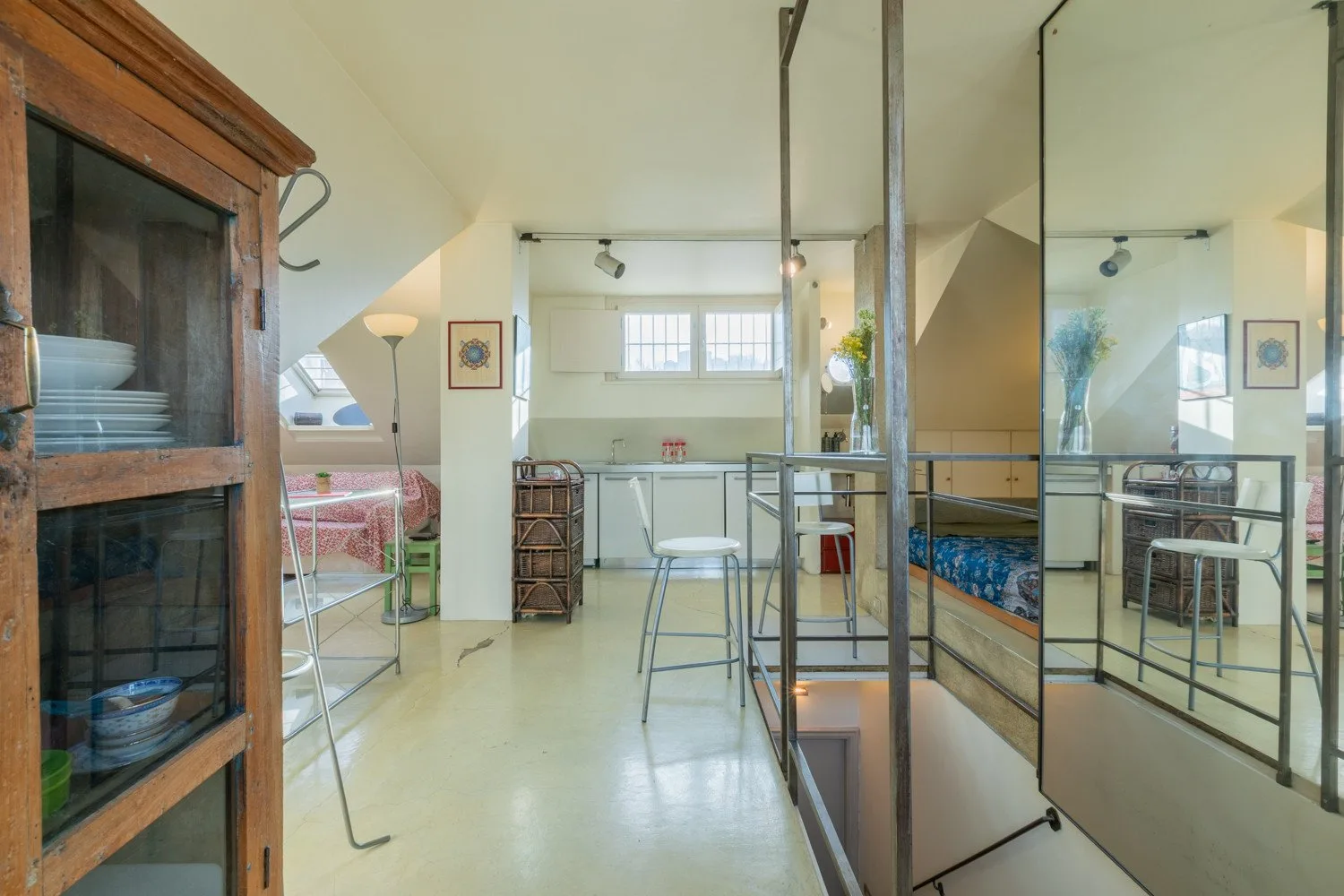 A bright loft interior with a raised sleeping area and metal railings.