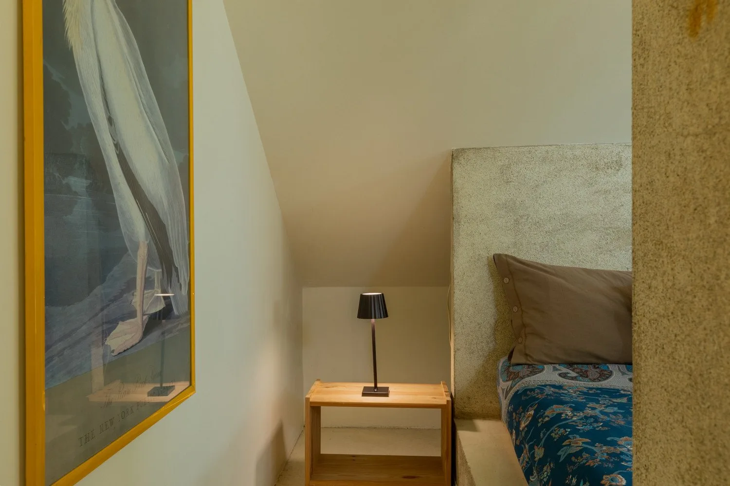 Un dormitorio con una mesita y una lámpara junto a la cama.