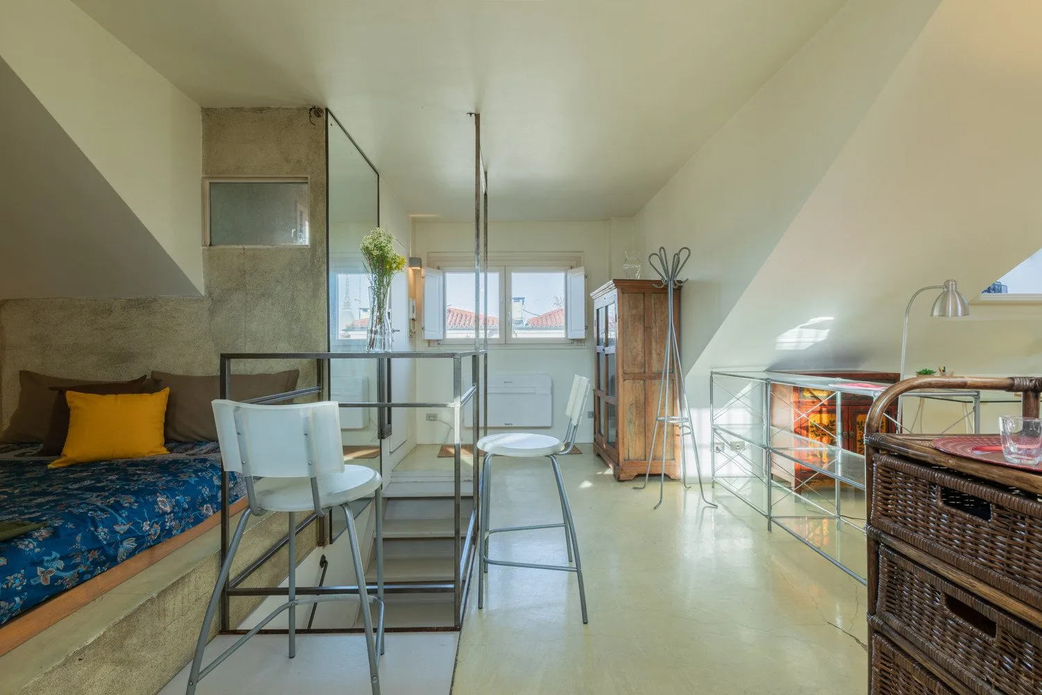 Una luminosa sala tipo loft con mesa y asientos junto a una cama elevada.