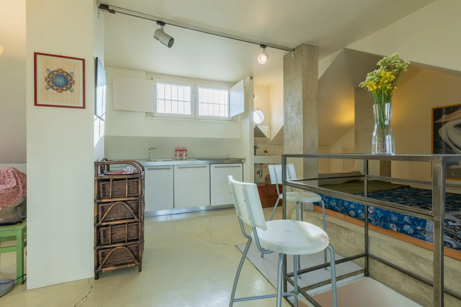Una cocina y comedor luminosos con gabinetes blancos y una mesa.
