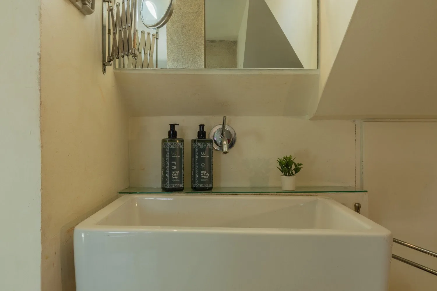 Un baño con una bañera rectangular y artículos de aseo sobre una repisa de vidrio.