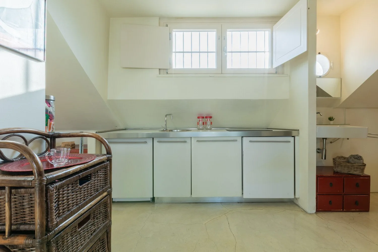 Una cocina luminosa con gabinetes blancos, una encimera y una ventana pequeña.