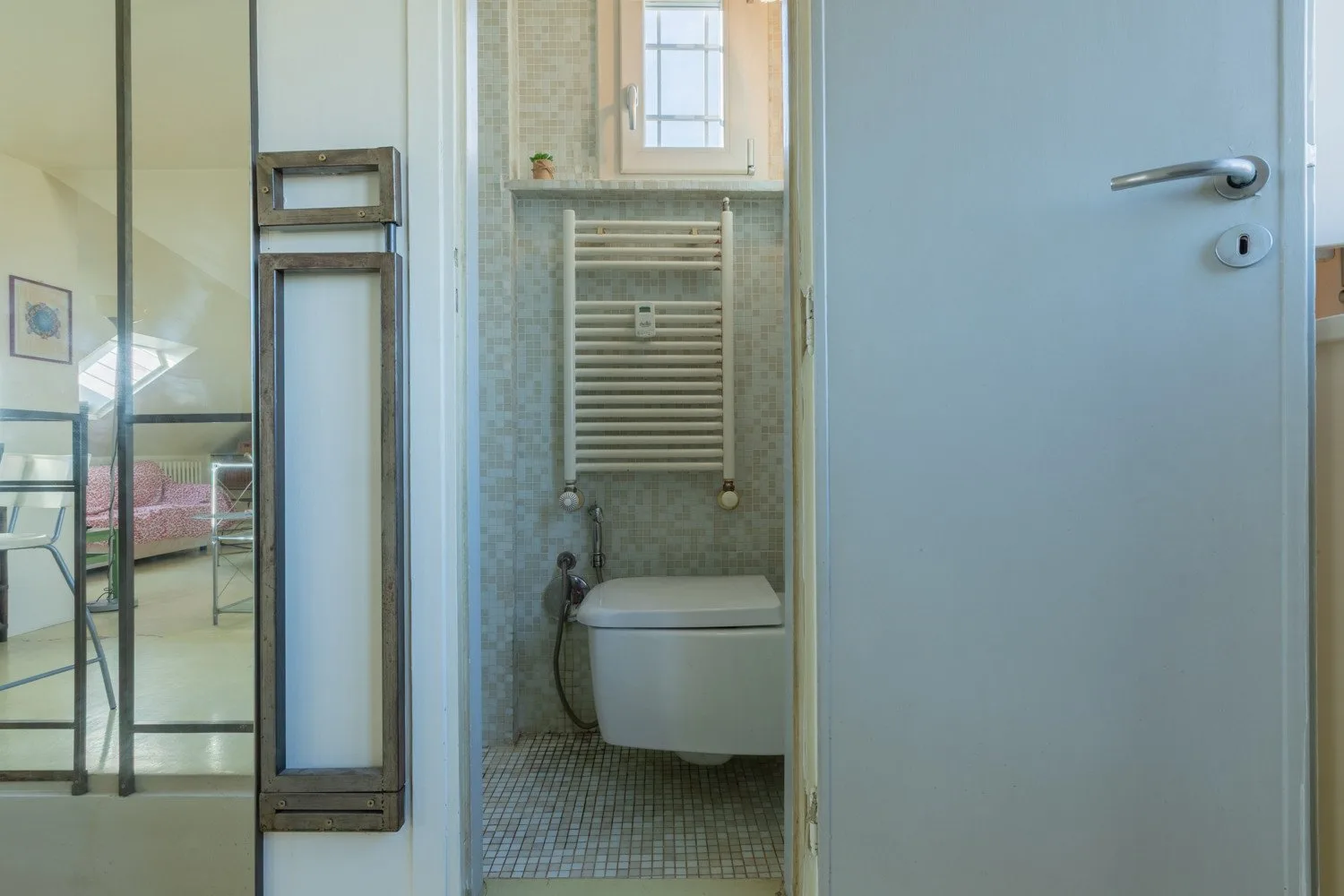 Un baño con un inodoro suspendido y paredes revestidas de azulejos.