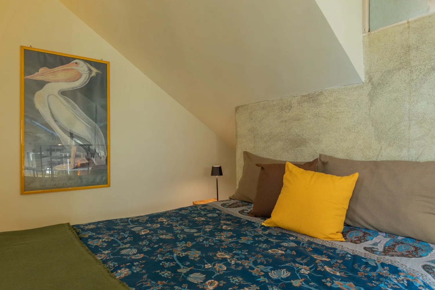 Un dormitorio con ropa de cama estampada, almohadas y un cuadro en la pared.