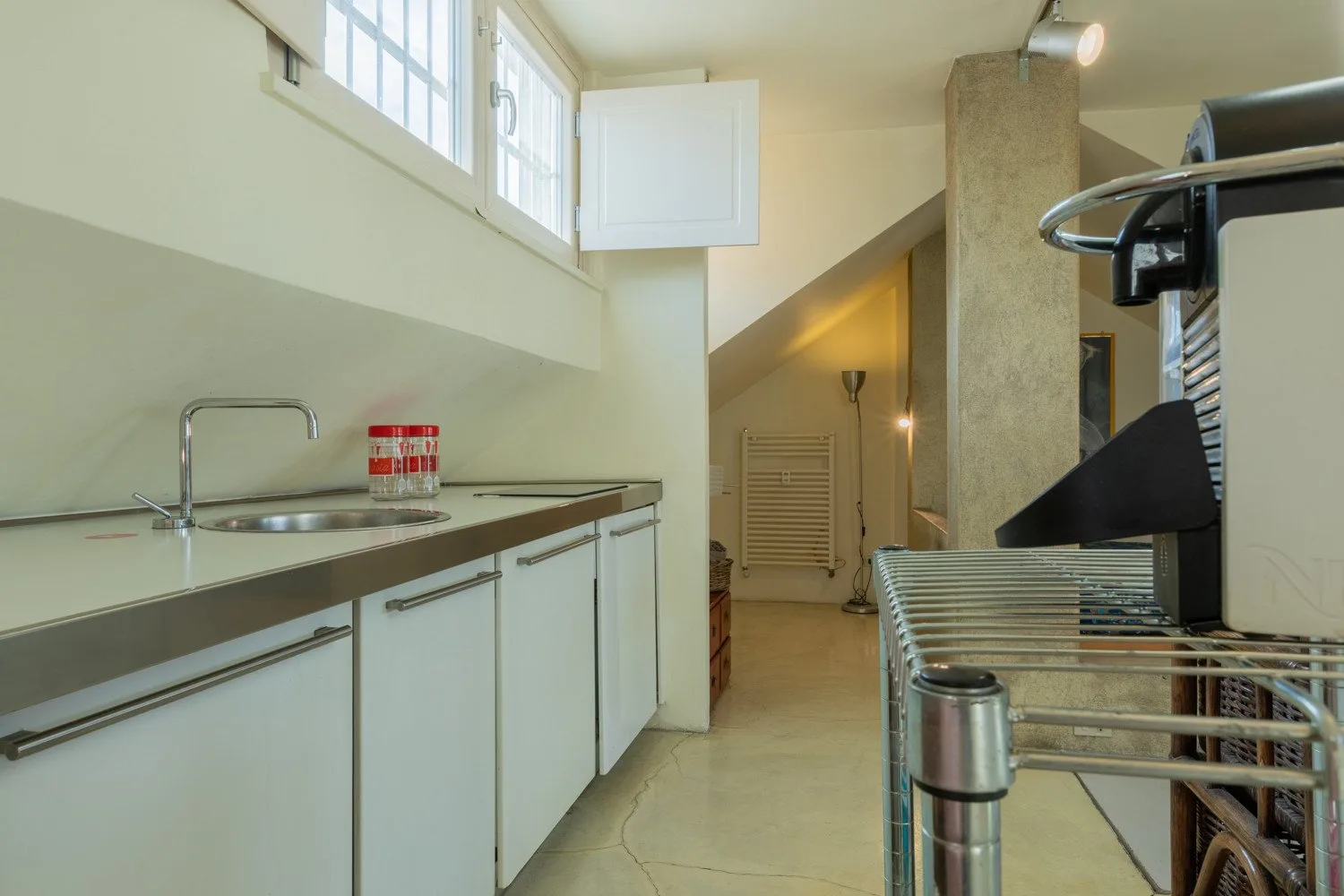Una cocina luminosa con gabinetes blancos, fregadero y electrodomésticos de acero inoxidable.