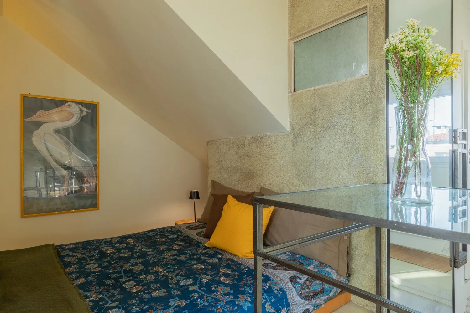 Un dormitorio con una cama baja cubierta con una colcha azul estampada.