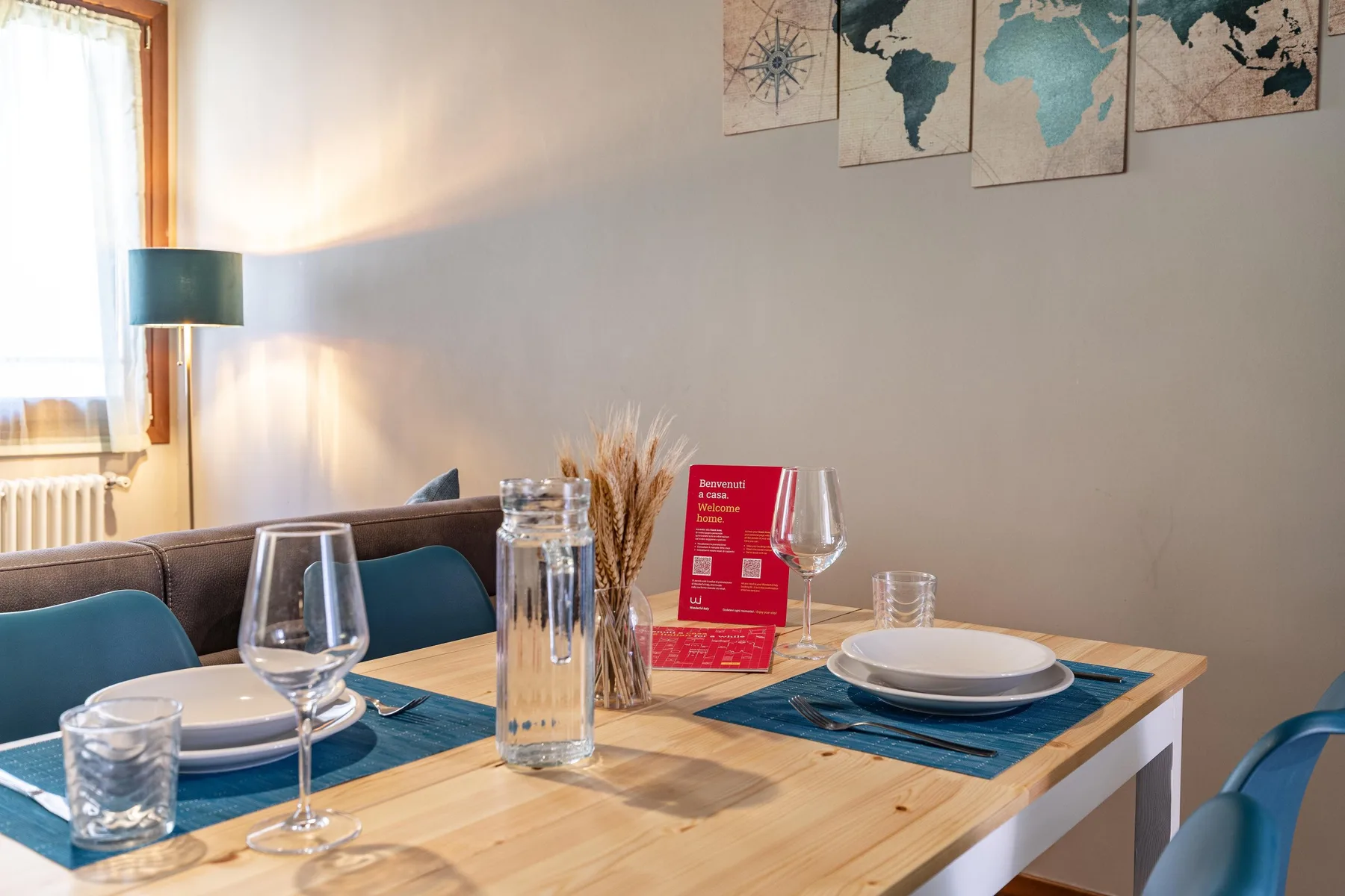 Una mesa de comedor está puesta con platos, copas y manteles individuales azules.