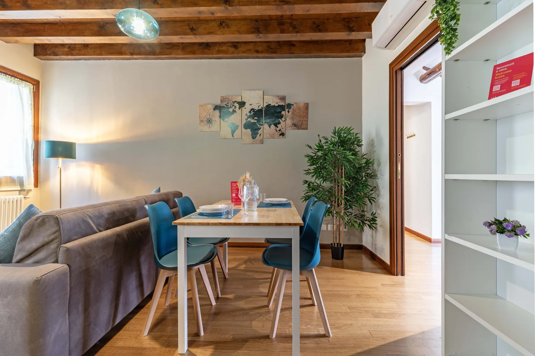 Comedor con mesa, sillas y una planta grande junto a una puerta abierta.