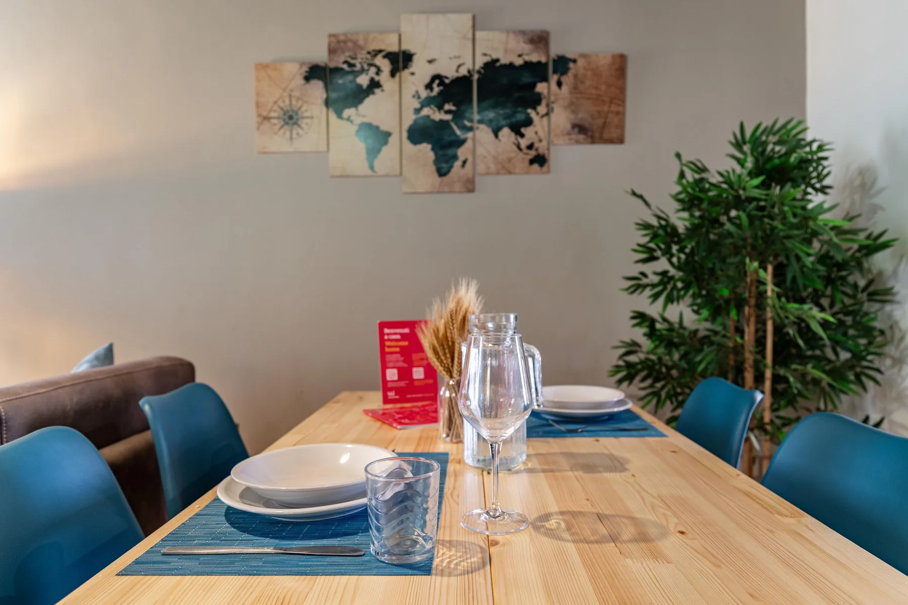 Un comedor con una mesa de madera puesta con platos y vasos.