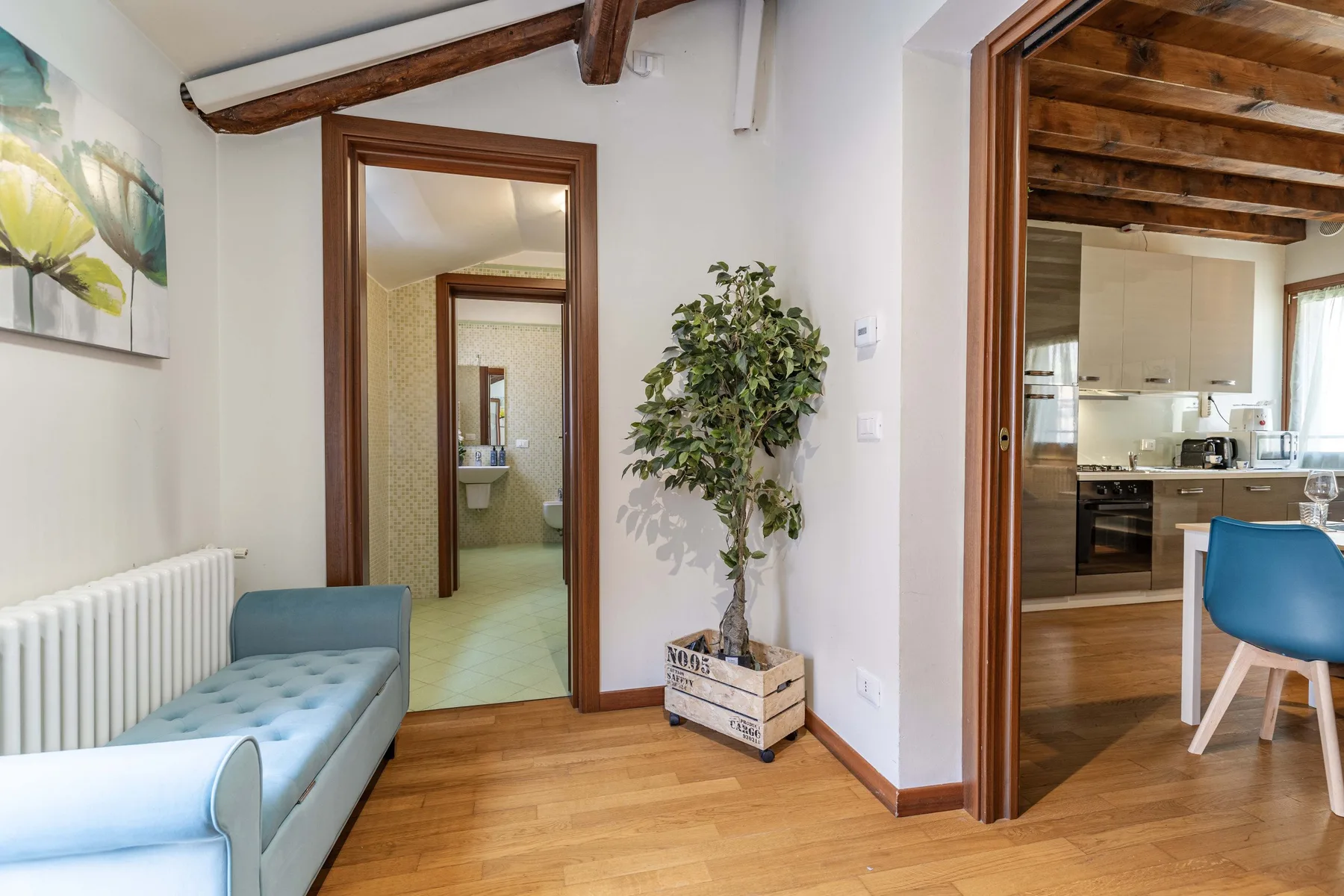 Un pasillo luminoso conecta una zona de estar con una cocina y un baño.