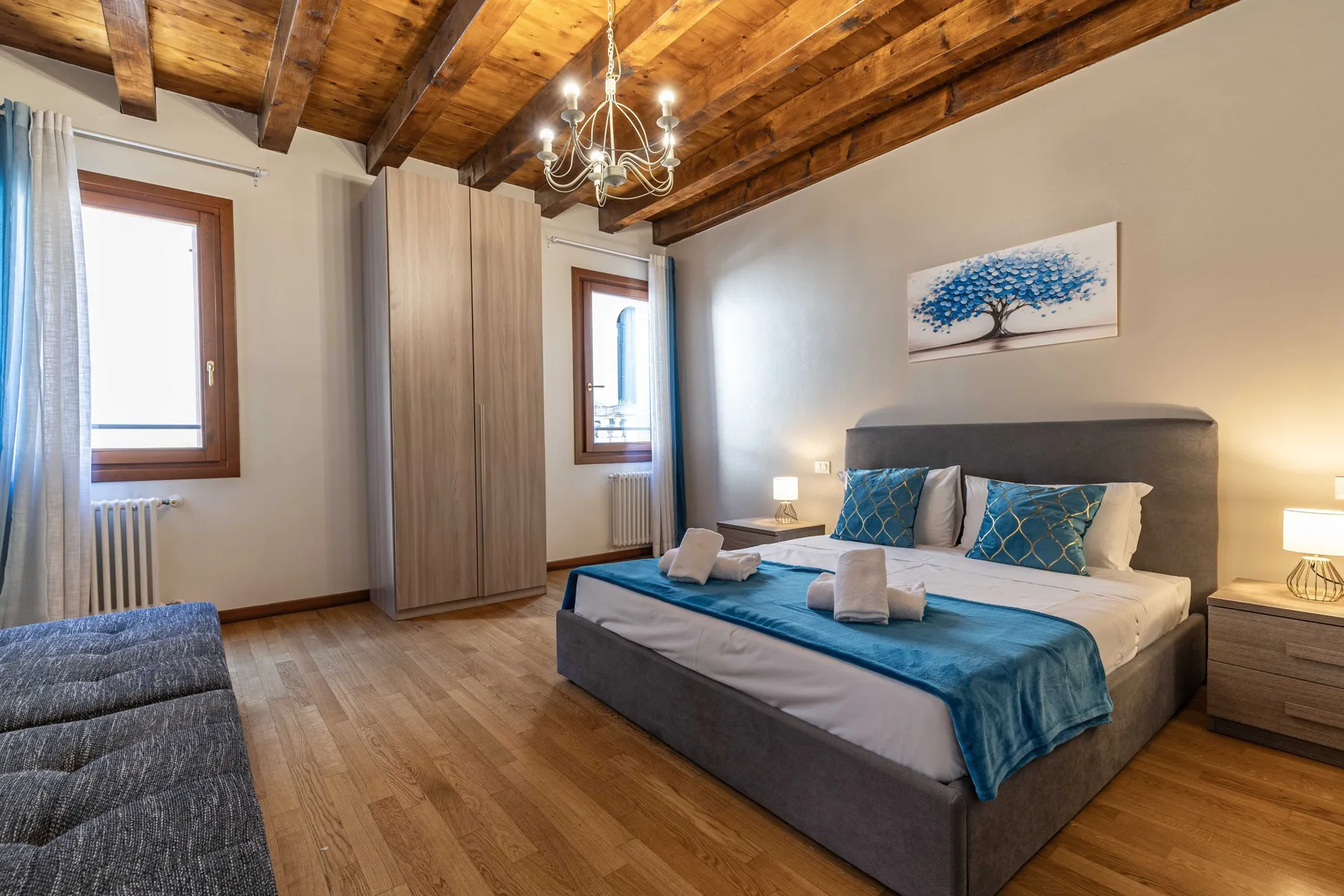 Un dormitorio con una cama, ropa de cama azul y vigas de madera expuestas.