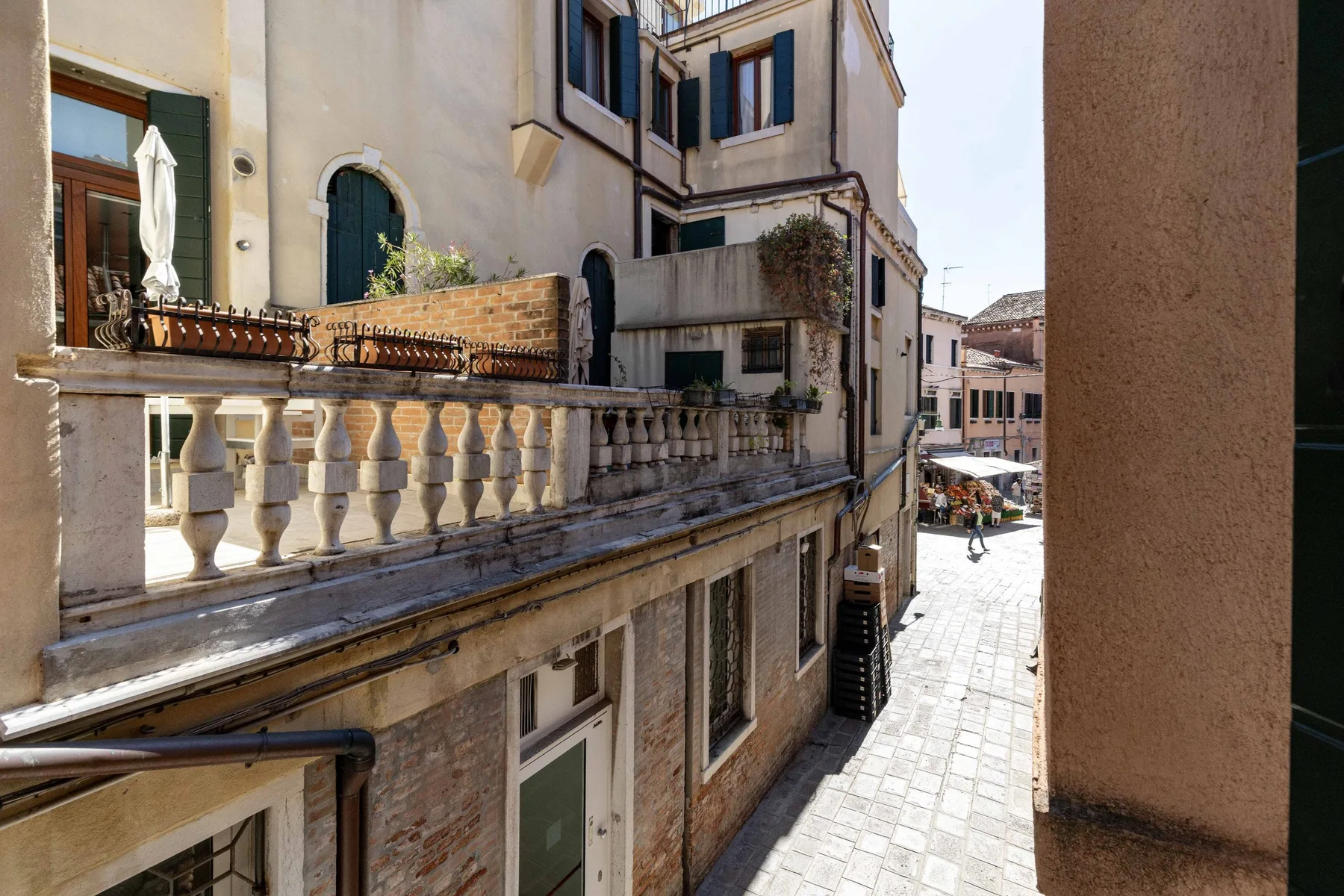 Un callejón estrecho pavimentado pasa entre edificios y balcones muy próximos.