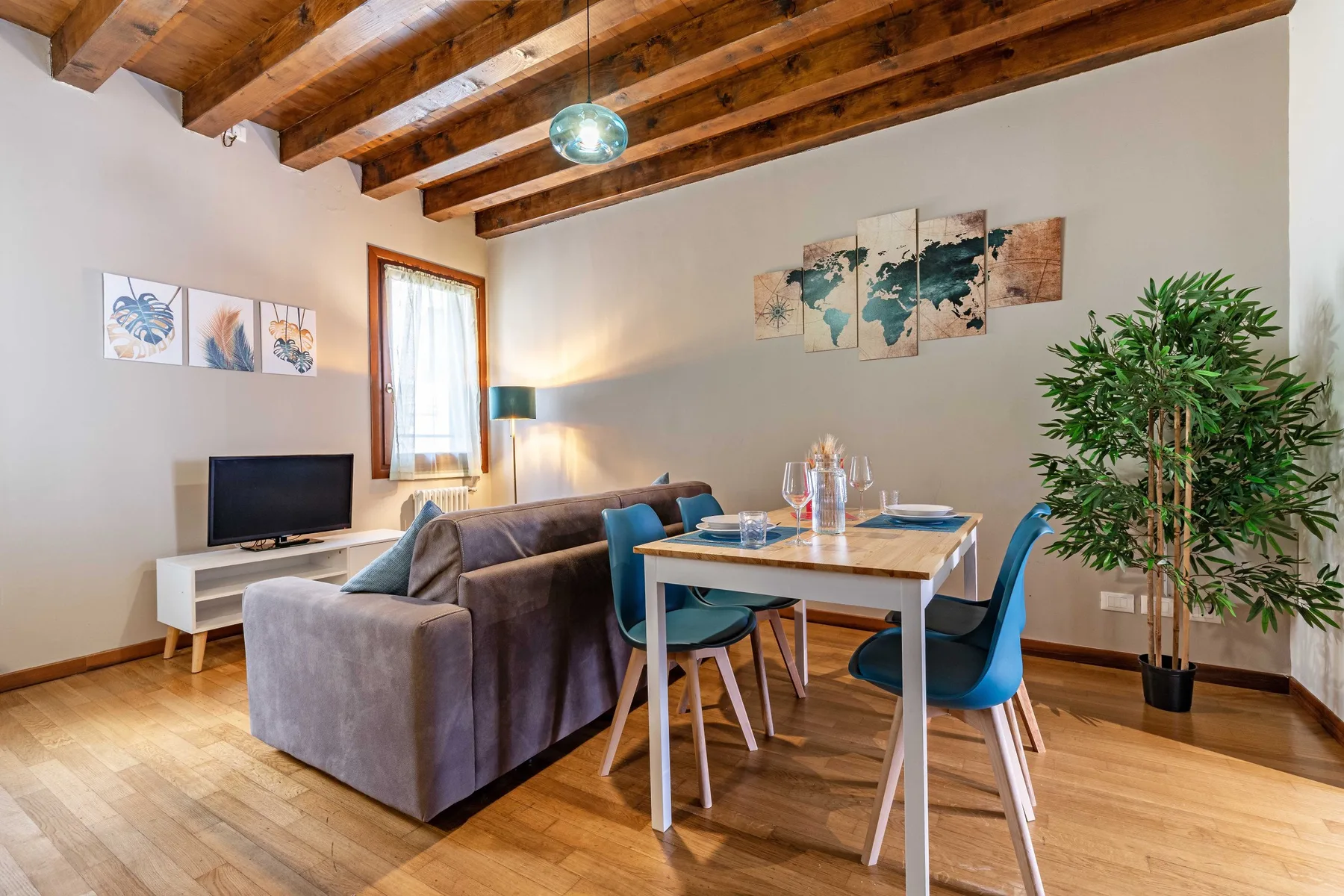 Una sala de estar y comedor con sofá, mesa y vigas de madera a la vista.