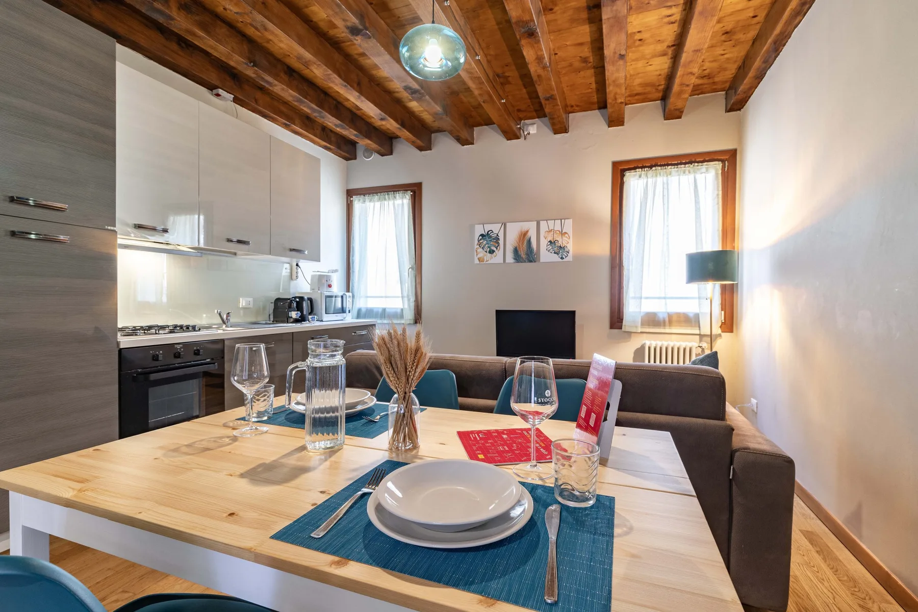 Comedor con una mesa de madera y una cocina abierta detrás.