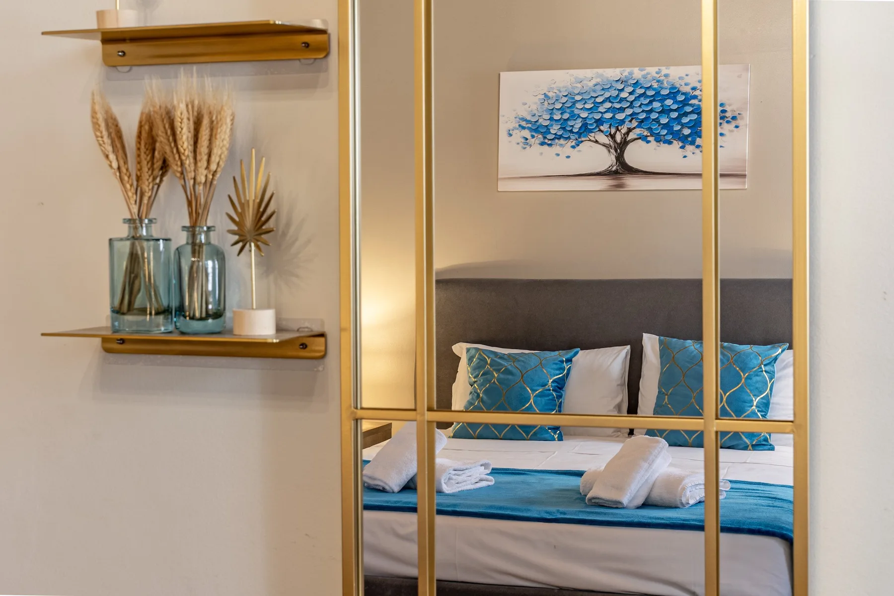 Un dormitorio con una cama arreglada y cojines decorativos azules.