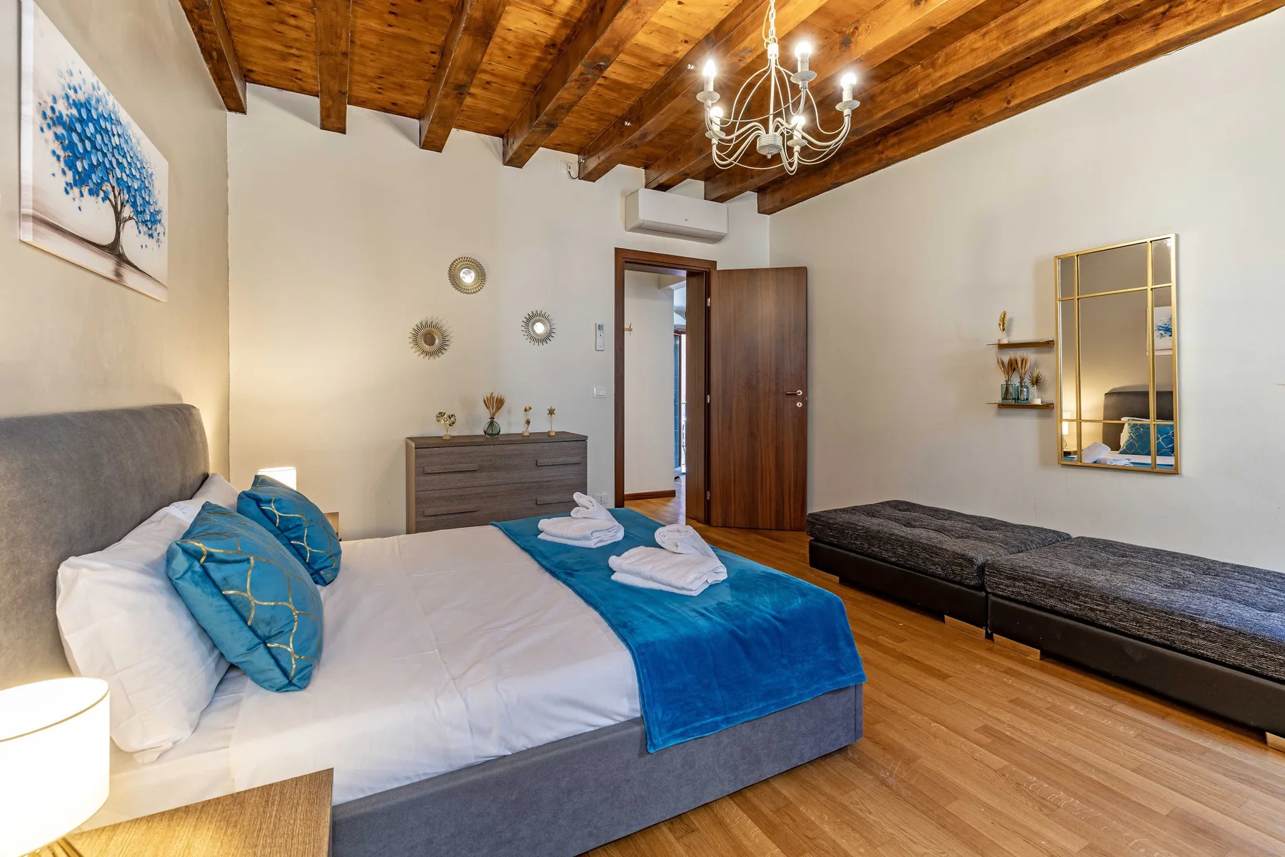 Un dormitorio con una cama grande, ropa de cama azul y techo de madera.
