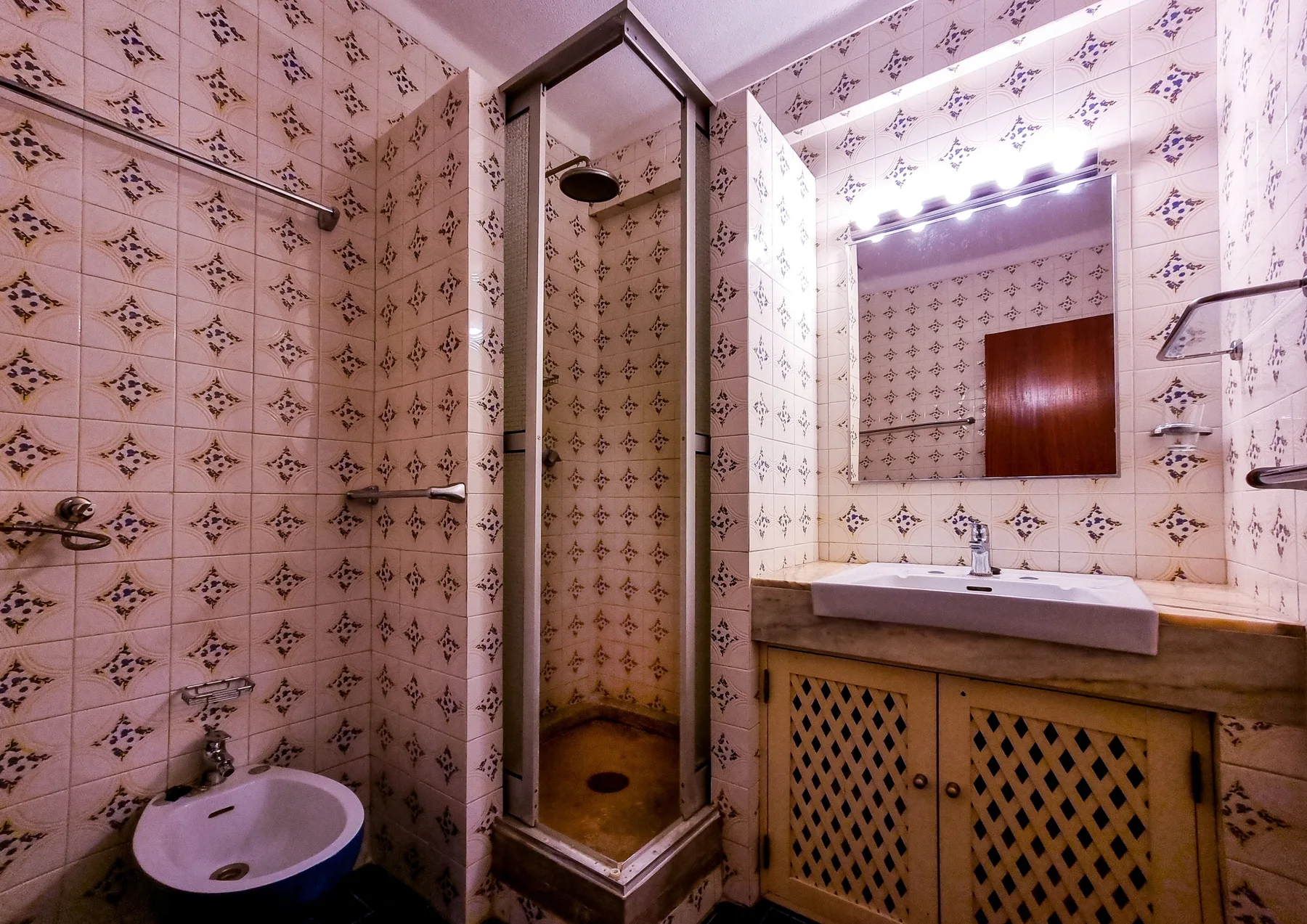 Un baño alicatado con ducha y lavabo bajo un espejo.
