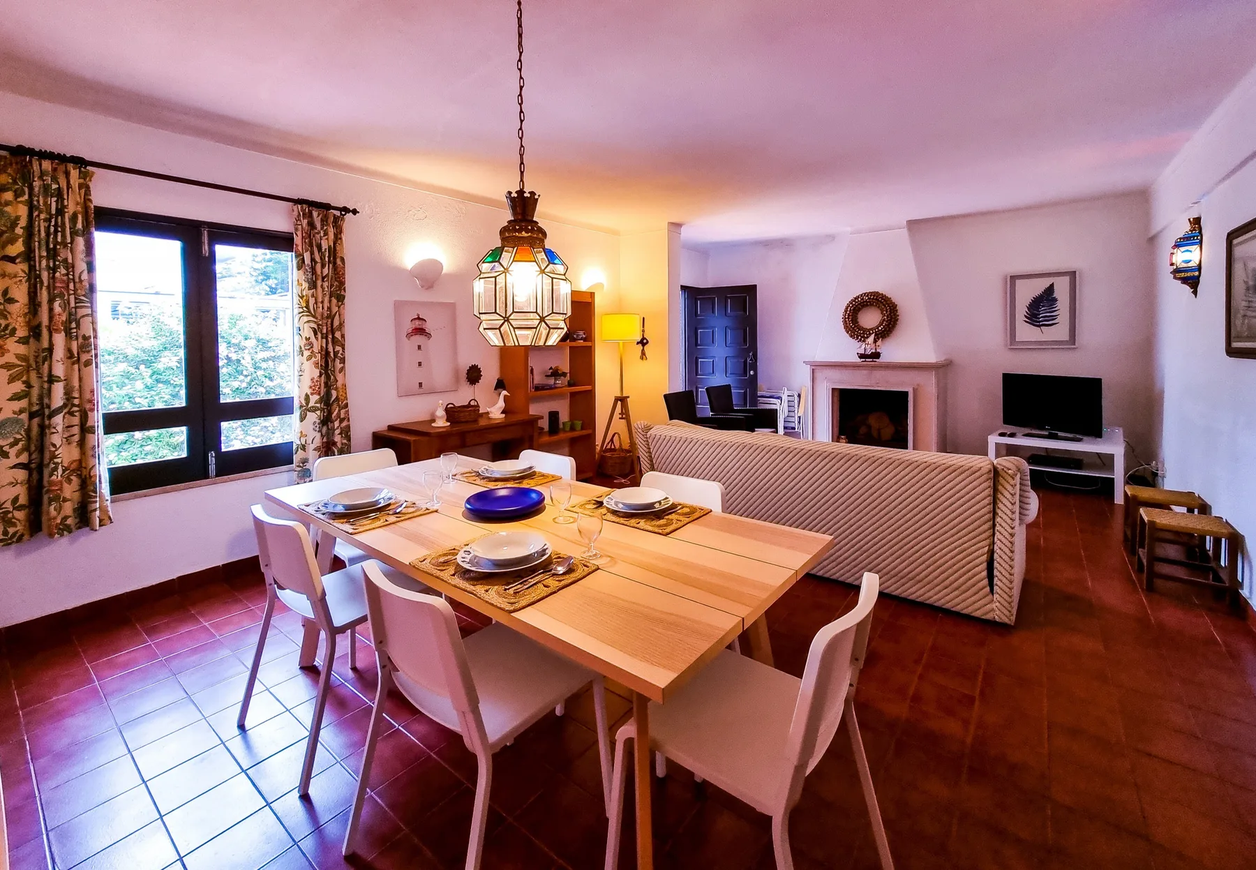 Un comedor y sala de estar con la mesa puesta y asientos.