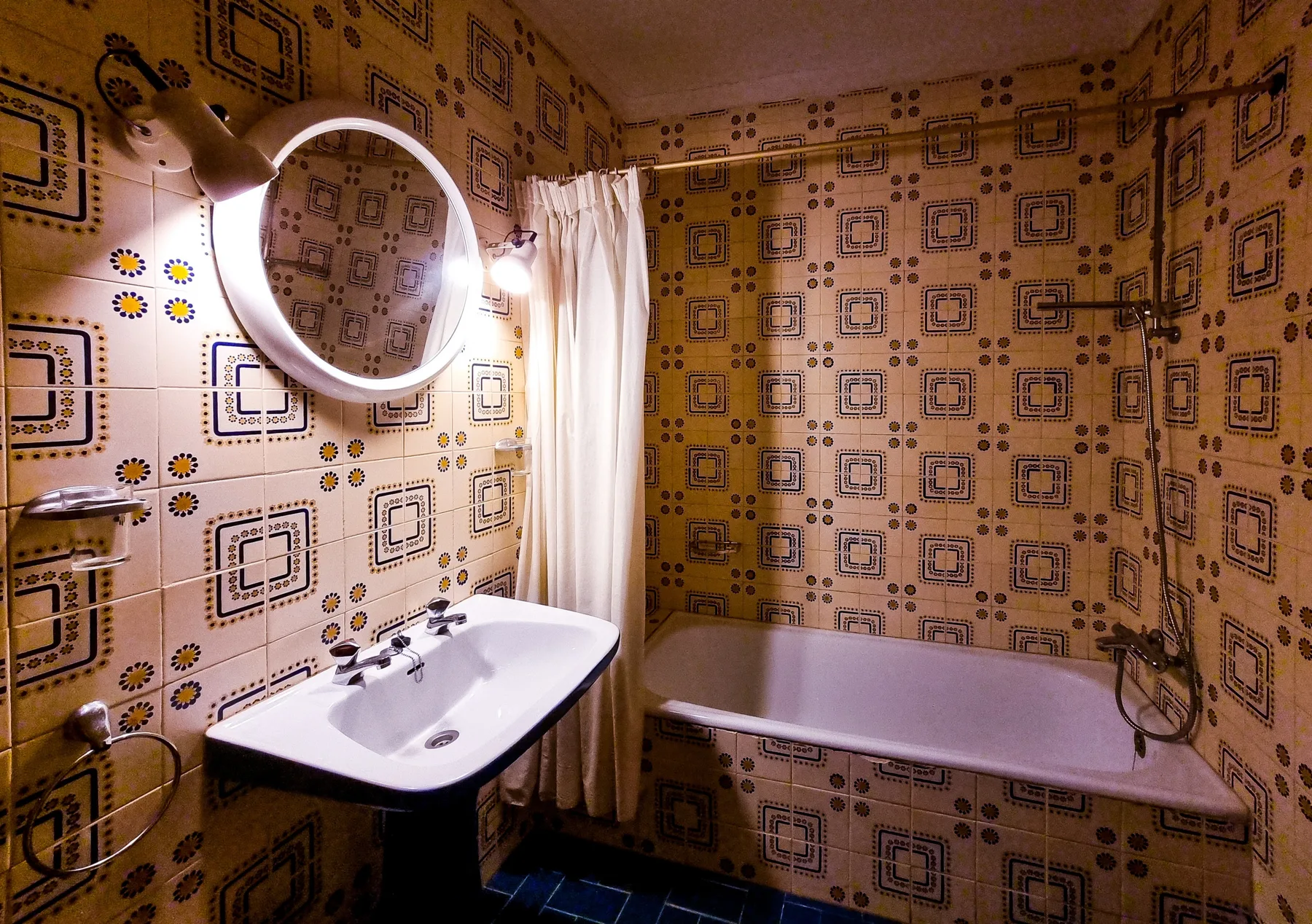 Un baño con bañera, lavabo y azulejos estampados en las paredes.