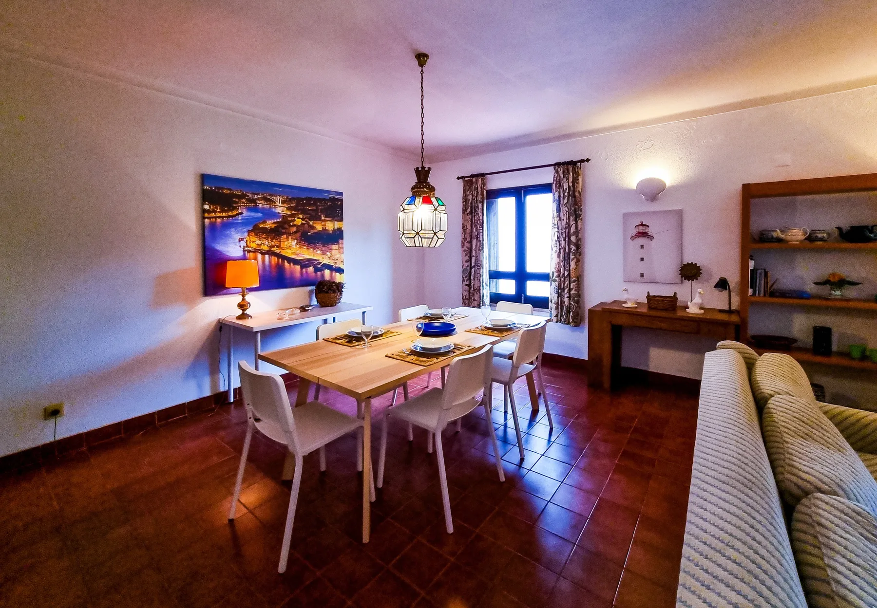 A dining area with a wooden table and chairs beside a window.