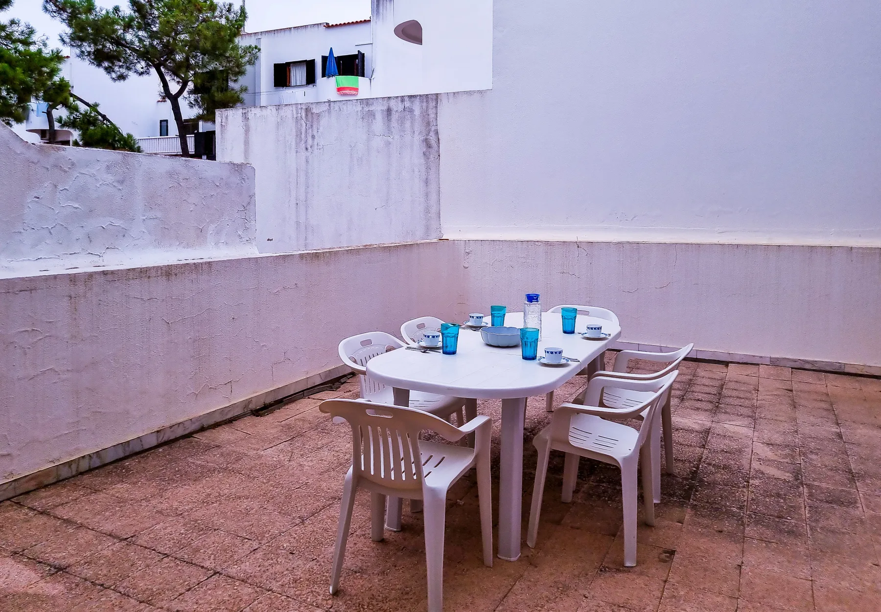 Una terraza exterior embaldosada con una mesa y asientos.