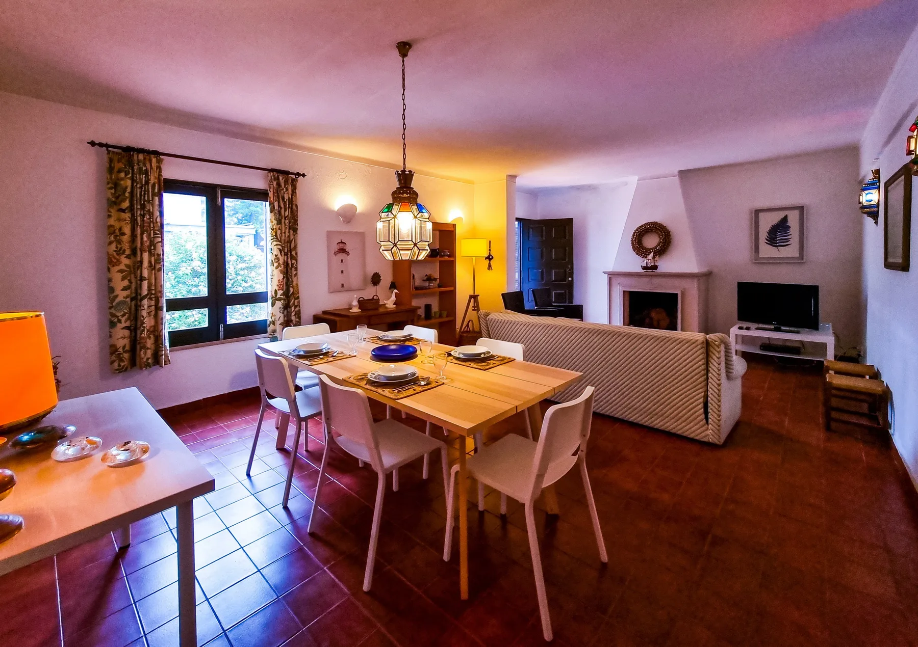 Sala de estar y comedor con una mesa de madera y asientos.