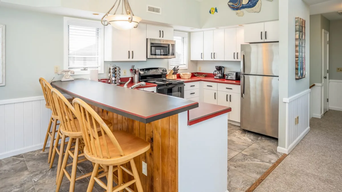 A bright kitchen with a large island and wooden bar stools.