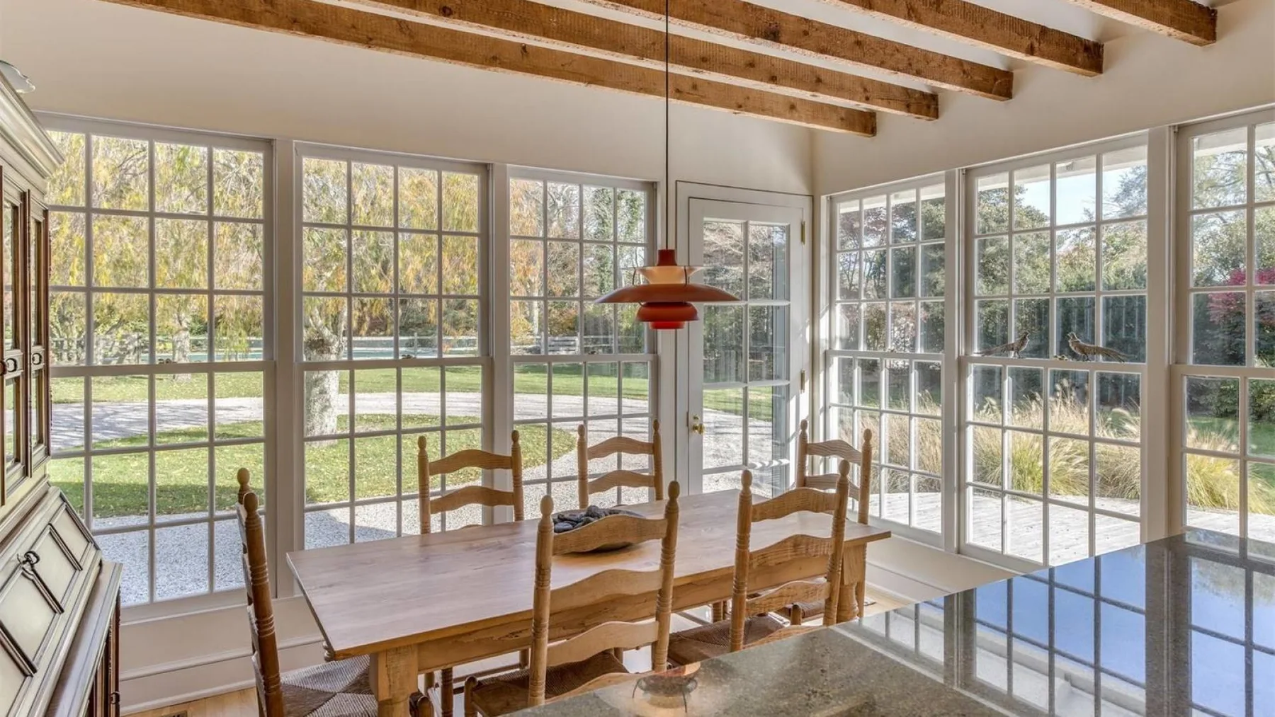 Un comedor luminoso con una mesa de madera junto a amplios ventanales.