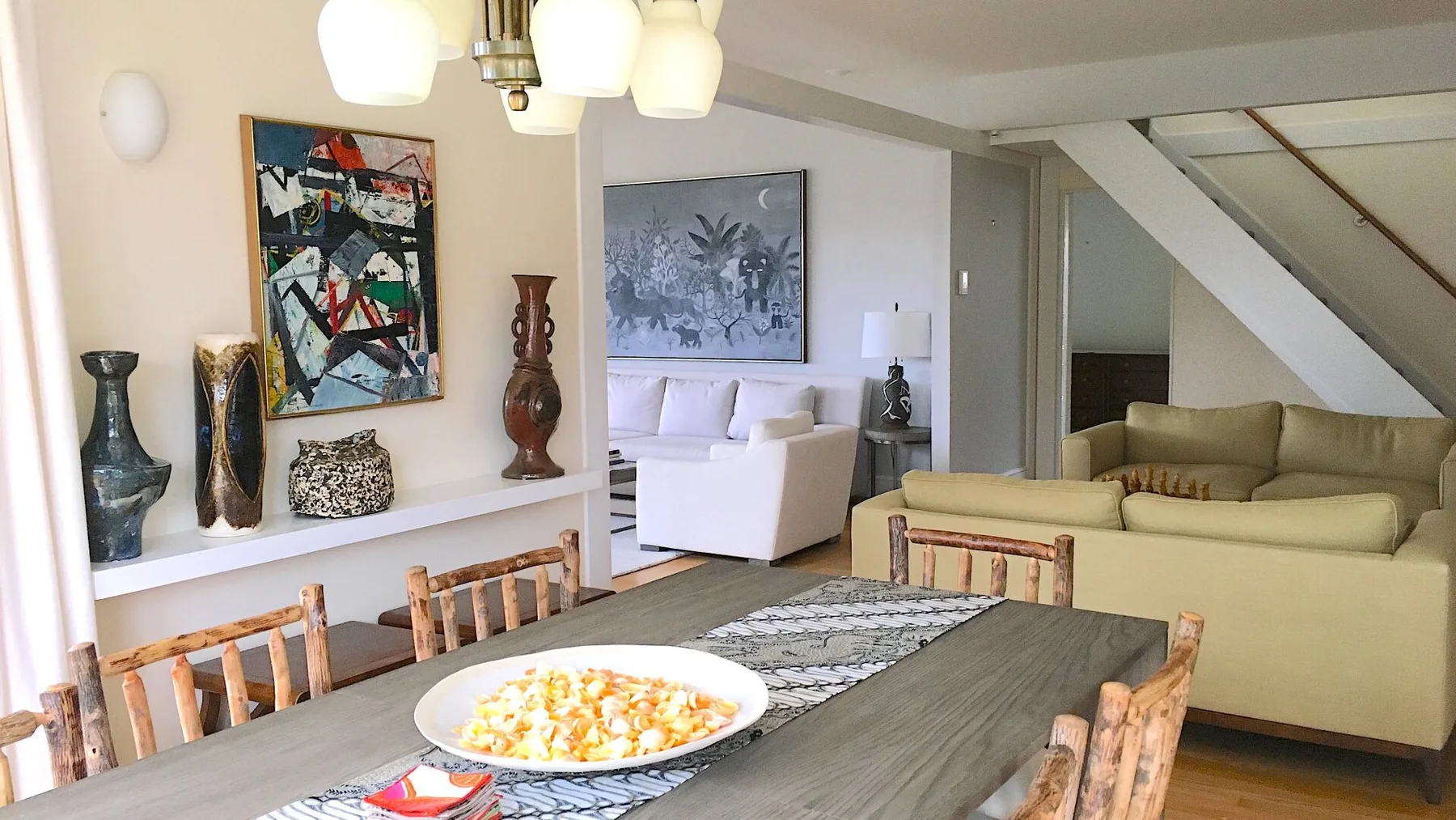 Una sala de estar con asientos alrededor de una mesa de comedor bajo lámparas colgantes.