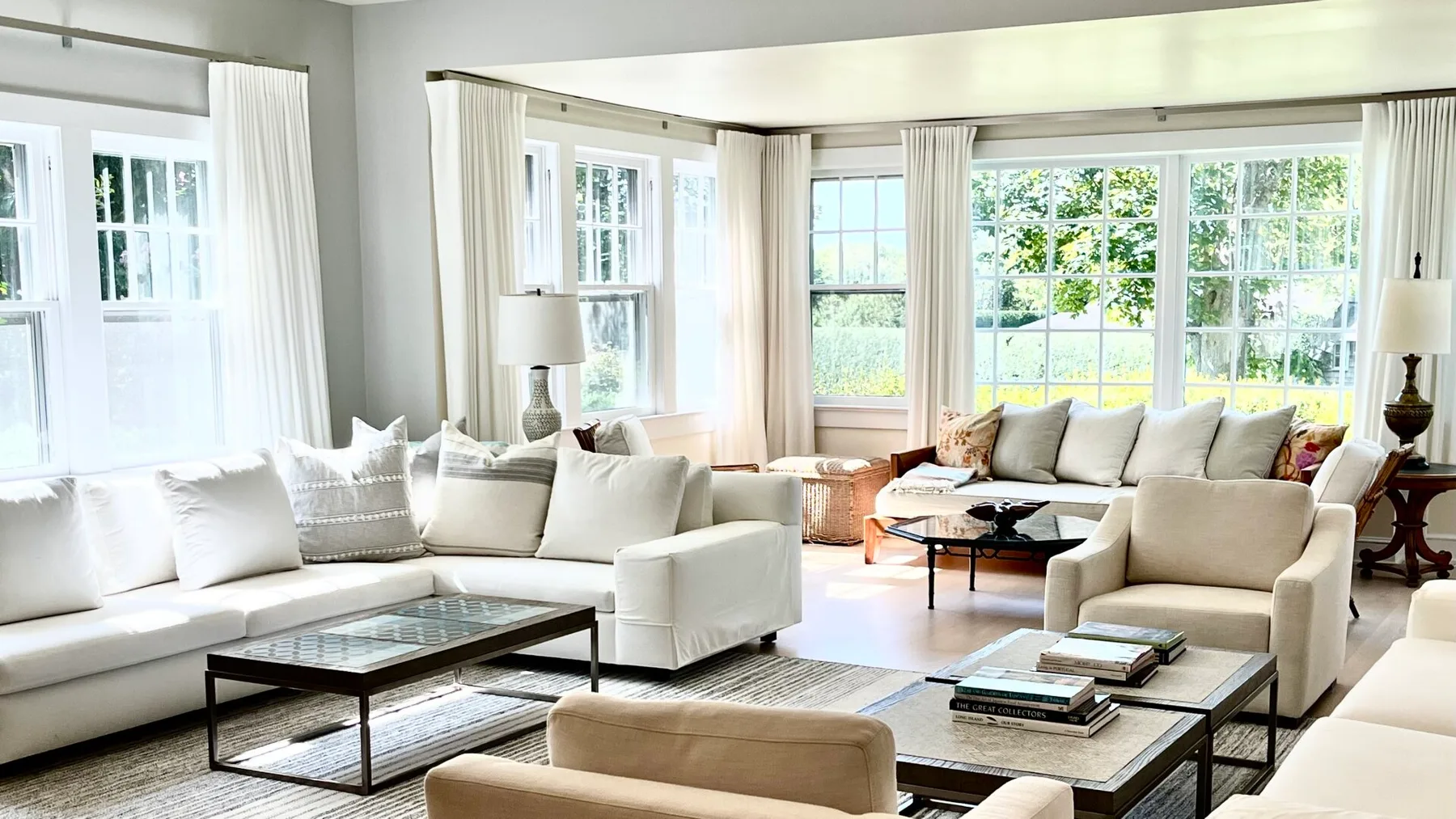 Una sala luminosa con asientos blancos y grandes ventanas con vistas a la vegetación.