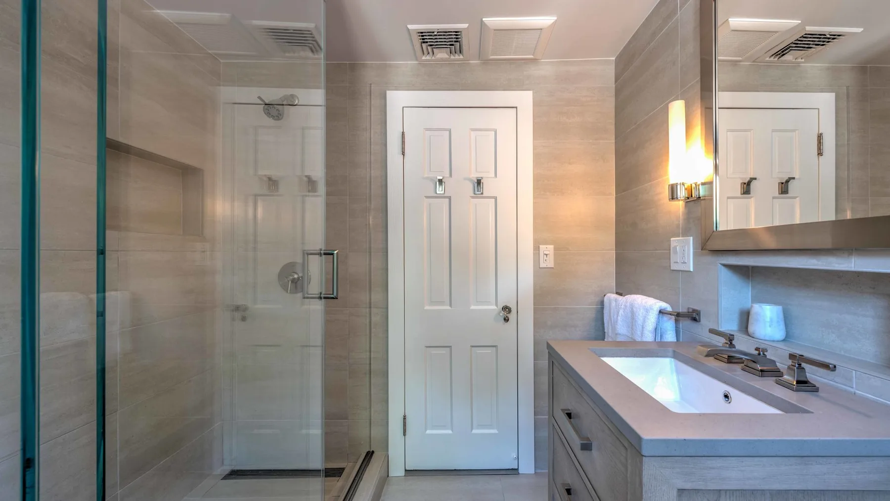 Un baño con una ducha de vidrio y un lavabo con mueble.
