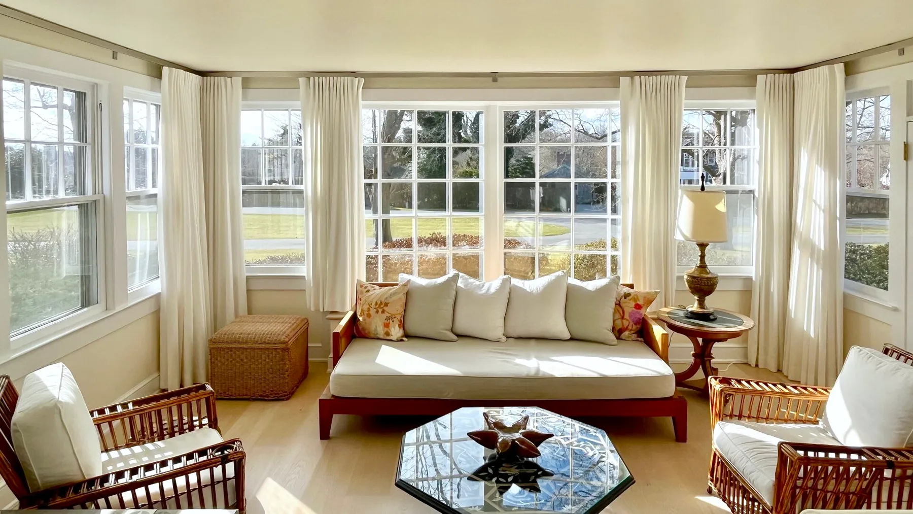 Un luminoso solárium con asientos acolchados y grandes ventanas con vistas al patio.
