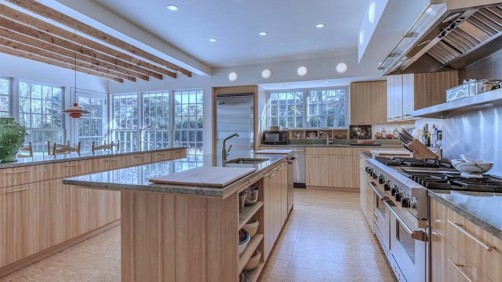 Una cocina amplia con gabinetes de madera, una isla central y grandes ventanas.