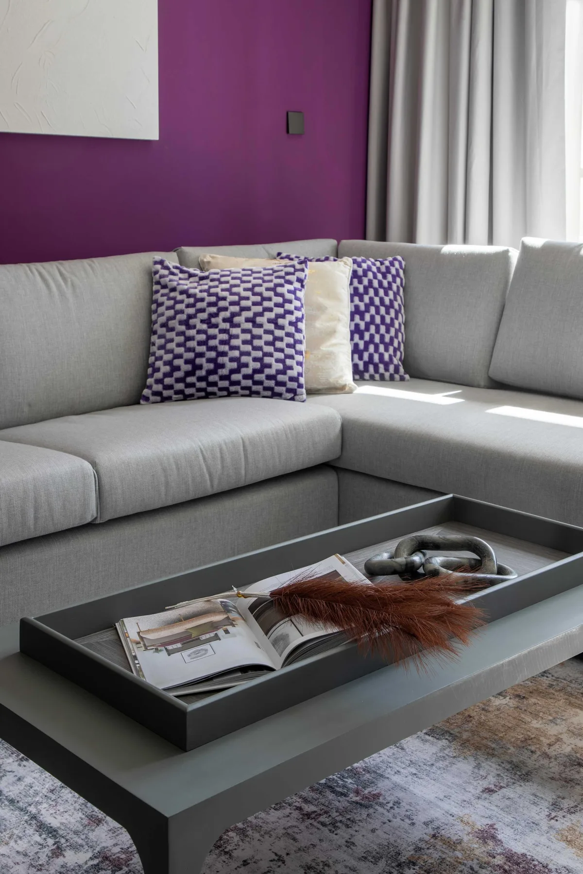 Una sala de estar con un sofá seccional gris y una mesa de centro baja.