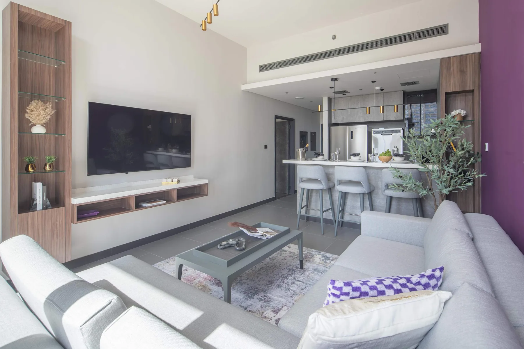 Una sala de estar moderna da a una cocina, con asientos alrededor de una mesa de centro.