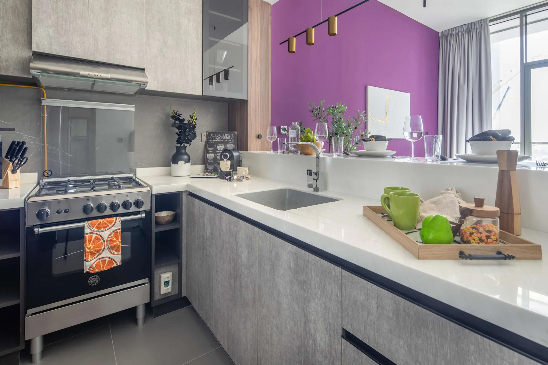 Una cocina moderna con estufa, fregadero y una llamativa pared morada.