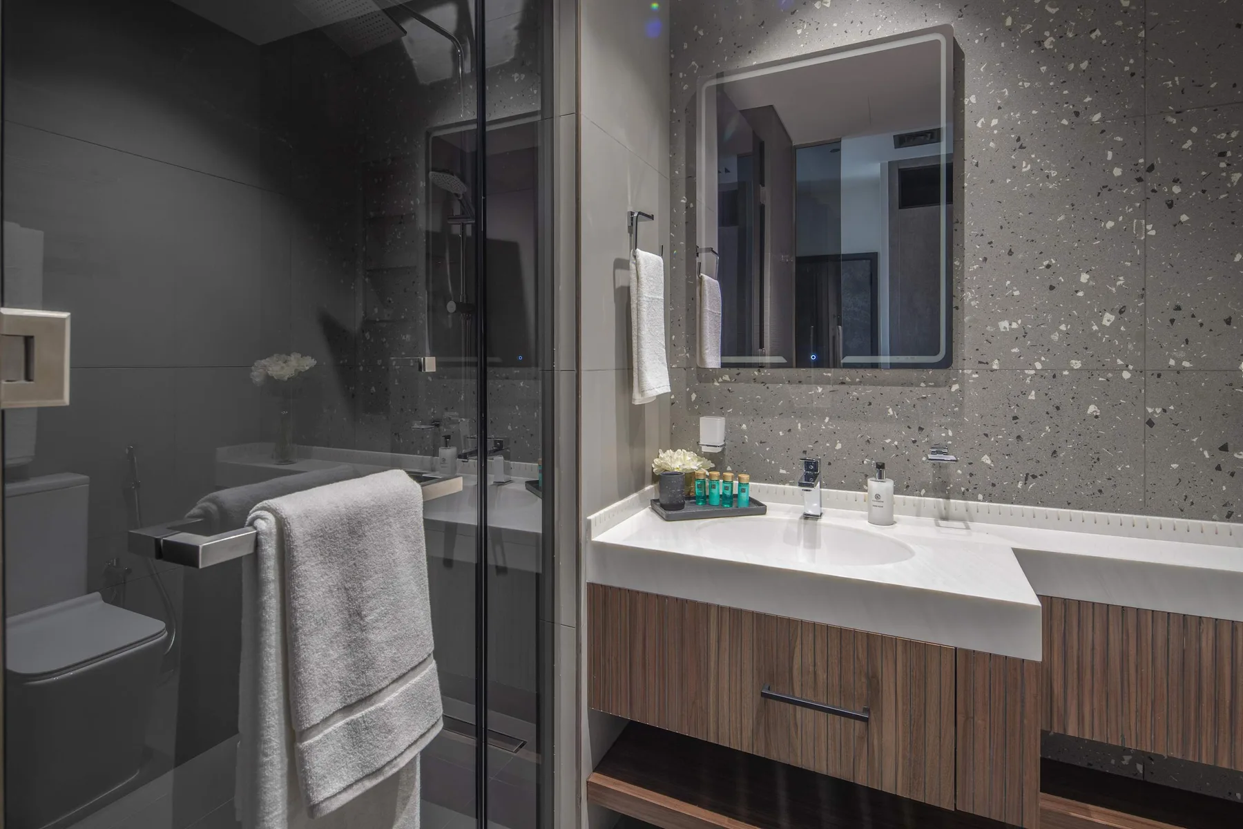 Un baño moderno con ducha de vidrio, inodoro y un amplio lavabo.