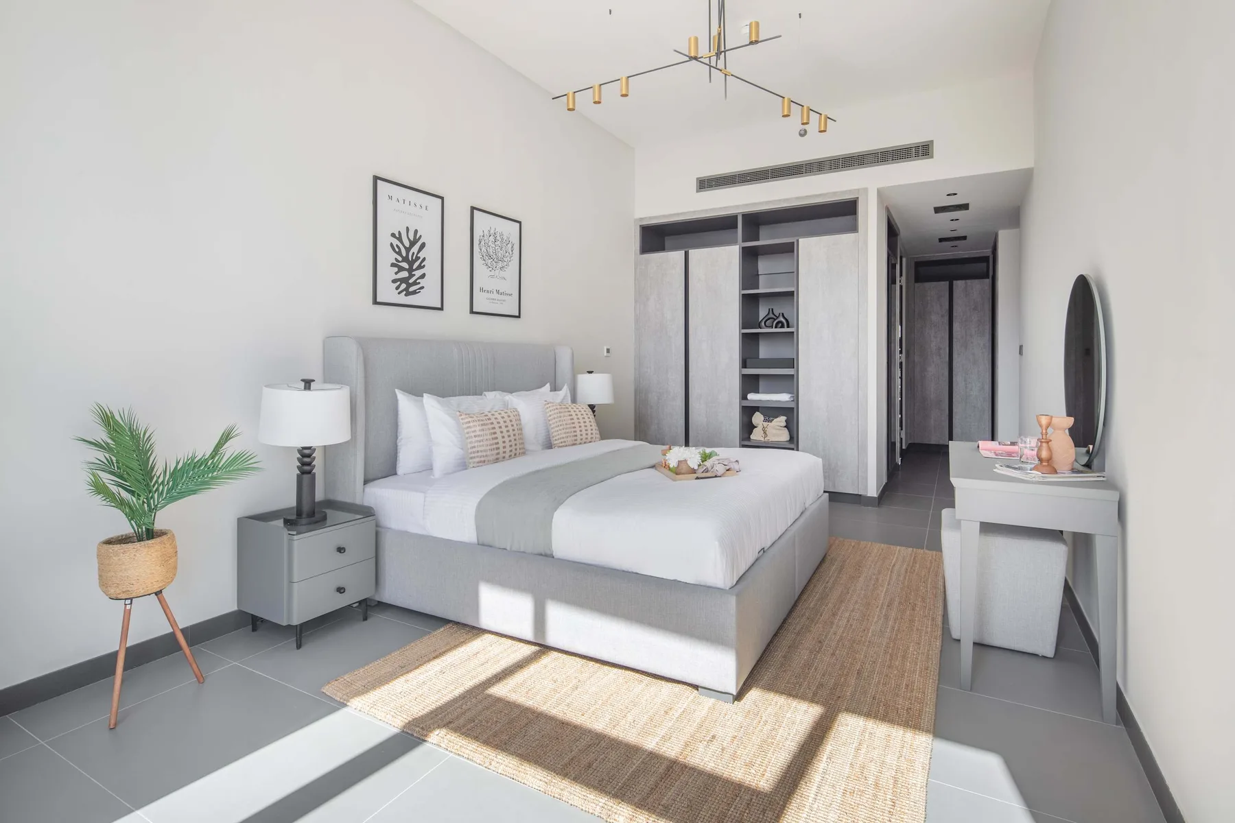 Un dormitorio luminoso con una cama tendida, mesitas de noche y un armario.