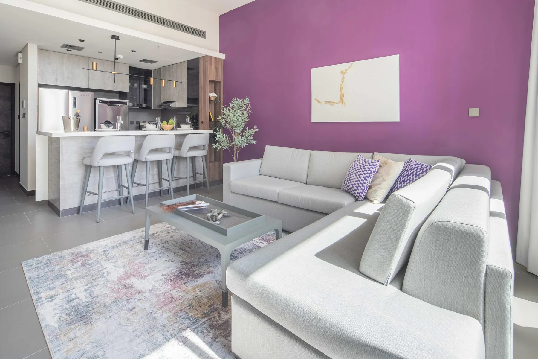 Una sala luminosa con una zona de asientos y una cocina abierta.