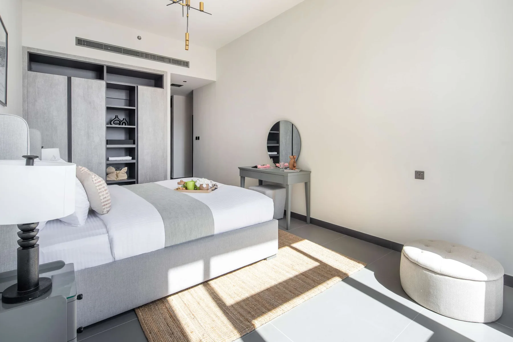 Un dormitorio luminoso con una cama y una pequeña mesa de tocador.
