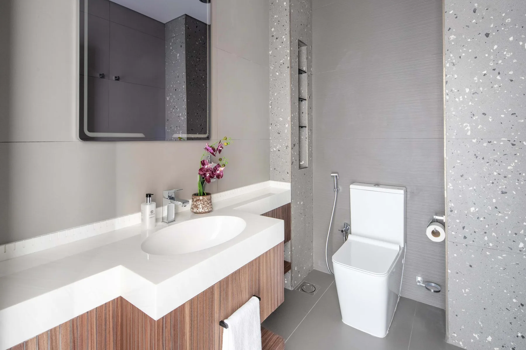 Un baño moderno con lavabo blanco, mueble y váter.